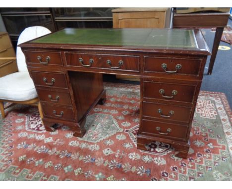 A mahogany twin pedestal desk fitted nine drawers with green tooled leather inset panel 