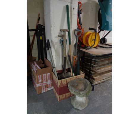 A box of assorted garden tools and a hand saw together with a stone bird bath 