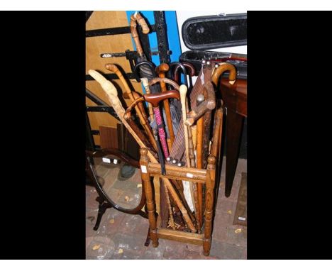 An oak stick/umbrella stand containing various walking sticks, umbrellas and a folding coat rack 