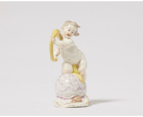 Putto als FortunaPorzellan, farbiger Aufglasurdekor, Vergoldung. Unglasierter offener Boden mit Ritzzeichen I, hinten geritzt