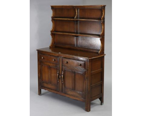 An Ercol oak sideboard/dresser fitted two shelves to the panelled back, the base fitted two frieze drawers above a cupboard e