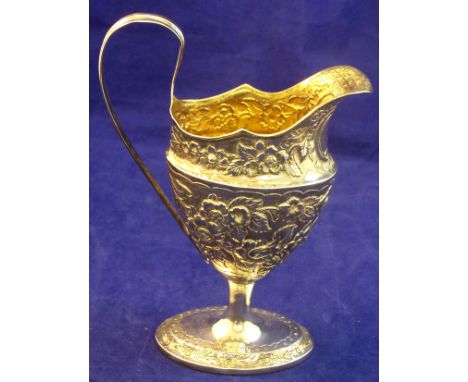 A Georgian silver helmet shape Cream Jug with loop handle, later embossed with flowers and leaves and on an oval pedestal foo