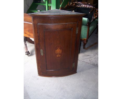 An early 19th century oak bow fronted Corner Wall Cupboard with stepped cornice, enclosed by a single panelled door with vase