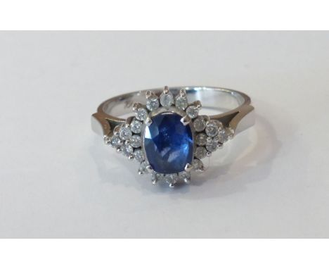 A white gold sapphire and diamond cluster Ring, the central mixed cut sapphire surrounded by brilliant cut diamonds, marked '
