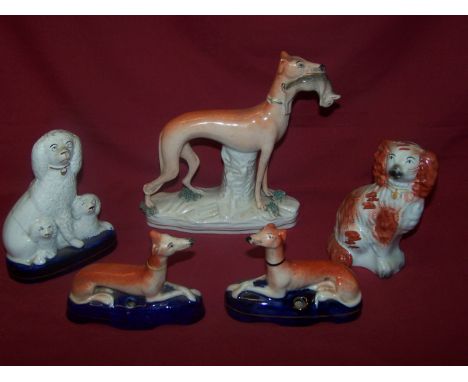 A Staffordshire pottery figure of a standing Greyhound with a hare in its mouth, two Staffordshire pottery pen holders and tw