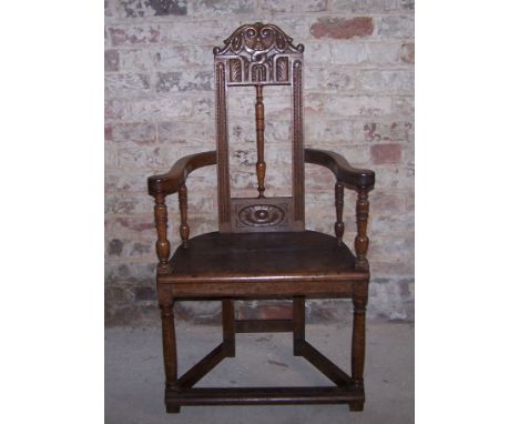 A Wainscot type country Elbow Chair with carved scroll cresting rail, open back, panel seat and swept arms, on turned support