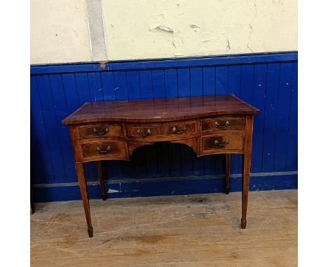 An early 20th century mahogany serpentine serving table, with a five drawer configuration, on square tapering legs with spade