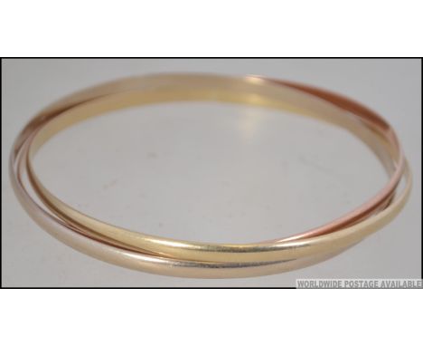 A 9ct gold 3 coloured puzzle bangle. Stamped to inside, diameter 6cms. Weight 18.2
