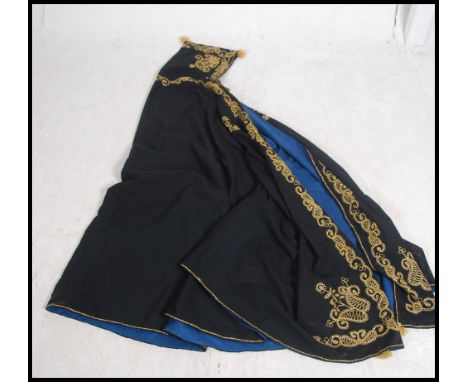 A full size cape / cloak, black with blue lined interior having gold coloured thread work embellishments to the borders and t