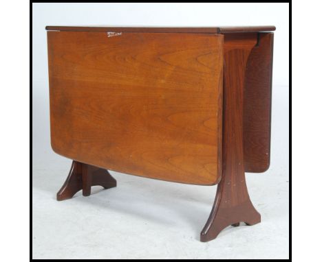 A 1970's teak wood drop leaf Danish influence dining table being raised on splayed legs with drop leaves supported by a gate 