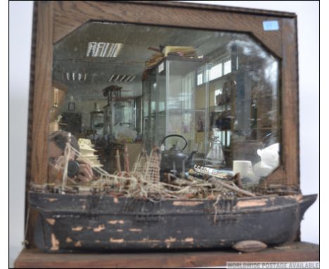 An unusual 20th century wall mirror with shelf having applied hull - shipwrecked boat being scratch built. Measures 57cm high