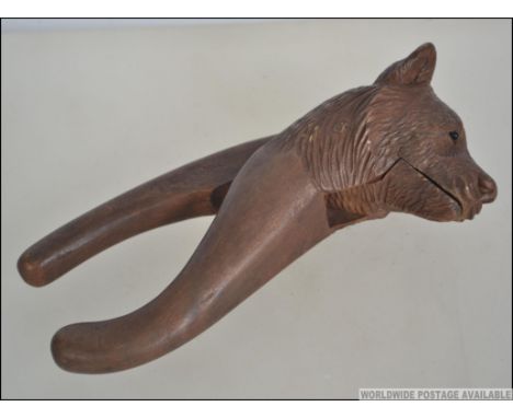 An early 20th century black forest wooden nut cracker in the form of a bear. Measures 17cm long.