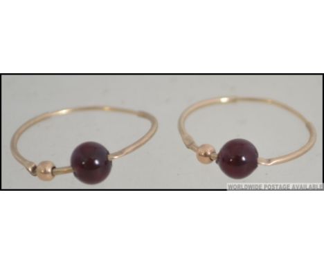 A pair of 9ct gold and ruby garnet glass stone bead adorned earrings. Total weight 0.8g. 