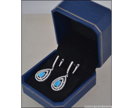 A pair of silver and blue opal drop earrings adorned with cz stone surrounds. Complete in the original presentation box. Size