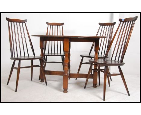 A set of 4 Ercol beech and elm stick back dining chairs raised on turned legs with saddle seat. Together with a drop leaf bee