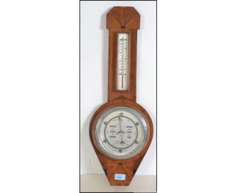 A 1930's Art Deco walnut barometer having silvered dial with thermometer to the neck. Measures 65cms long.