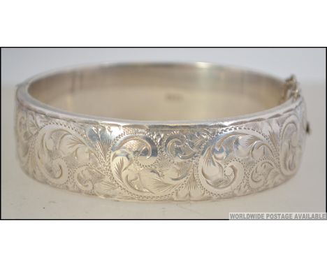 A heavy silver hallmarked ladies rococo bangle being chase decorated complete with the safety chain. Hallmarked for C.P.S.Bir