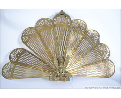 A 20th Century brass metamorphic peacock firescreen having eight fan out leaves with a Griffin base. Measures 57cm high.