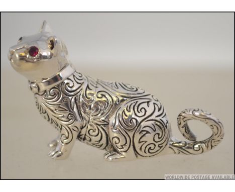 A unusual silver miniature figure of a cat being chase decorated with ruby glass stone eyes. Weight 20.3g Measures 5cms long