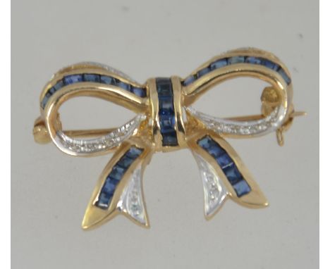 A 9ct gold sapphire and diamond brooch in the form of a bow. The channel set square sapphires with diamonds elsewhere approx 