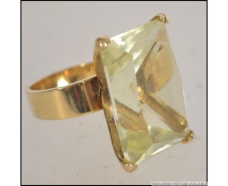 A 14ct gold oversized ladies dress ring having a large citrine coloured cushion cut glass stone. Marked 585 and 14k to band. 