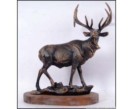A large cast iron vintage style figure of a Stag on a wooden podium. 37cm long. 