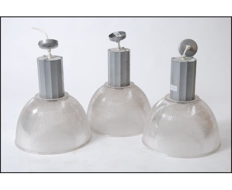A set of contemporary factory pendant lights by Compact Lighting ) model no 550047J/X5501 , each with clear plastic shades