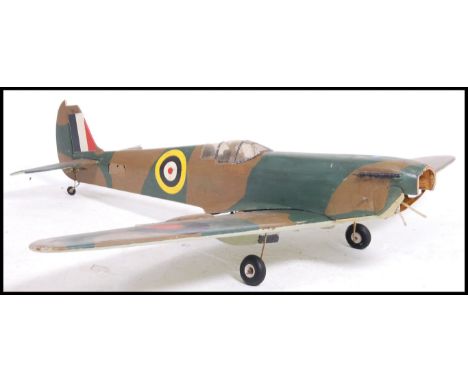 A large vintage scratch built balsa wood constructed remote controlled Spitfire aeroplane. Painted in camouflage paint with R