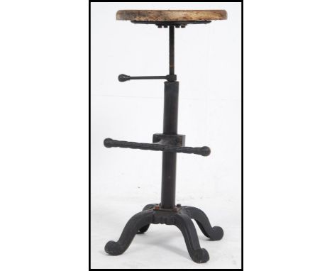 A vintage cast - wrought iron Industrial stool with foot rest having a later wooden carved seat of lozenge form. Measures: 76