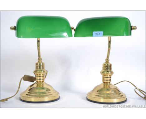 A pair of 20th century bankers desk lamp having a green glass shade being raised on a brass stands with terraced bases. Measu