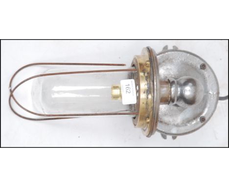 An Industrial cast metal heavy set bulkhead / dairy lamp with caged pendant style bulb on polished steel wall mount being re-