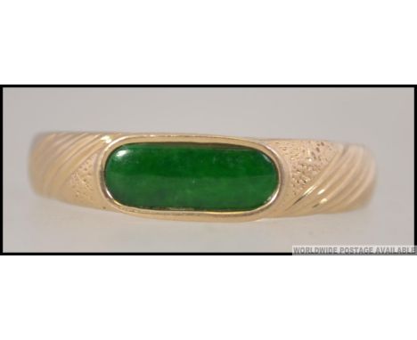 A 14ct gold and apple green jade ring. The ring inset with lozenge shaped jade stone. Size R.5 / Weight 3.4g