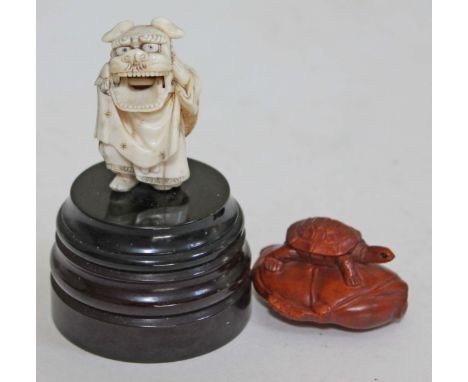 A Japanese carved ivory okimono depicting a man wearing a Shi Shi Dog mask with hinged jaw circa 1900, on later base, height 