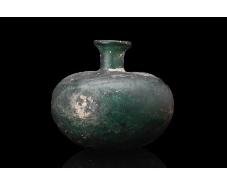 Ca. 1000 AD. A glass flask with an onion-shaped body crafted in a mesmerizing deep green hue, evoking a sense of timeless ele