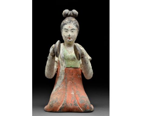 Ca. 618-907 AD. A terracotta figure of a kneeling female musician wearing a long flowing gown with an orange skirt and green 