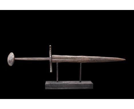Ca. 1300-1500 AD. A short iron double-edged dagger with a slightly curved sculptured cross guard with incised decoration and 