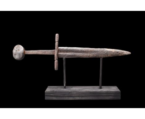 Ca. 1300-1500 AD. A short iron double-edged dagger with a straight sculptured cross guard with incised decoration and taperin