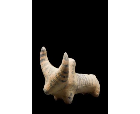 Ca. 3rd Millennium BC. A creme-coloured ceramic figurine of a zebu bull with rondel eyes. Painted with stripes on the back, a