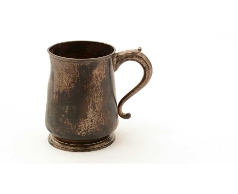 An early 18th Century Chanel Islands silver mug, slightly bellied, with a tucked-in base and a spreading circular foot, leaf-