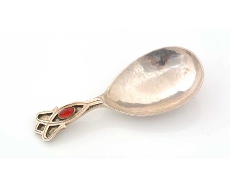 A George V silver caddy spoon with a hammered, drop-shaped bowl, the terminal cabochon set with an oval, red hardstone boss, 
