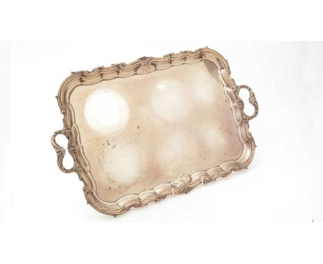 An Edwardian silver two handled tea tray, of shaped rectangular outline with a shell and scroll border, by William Hutton and