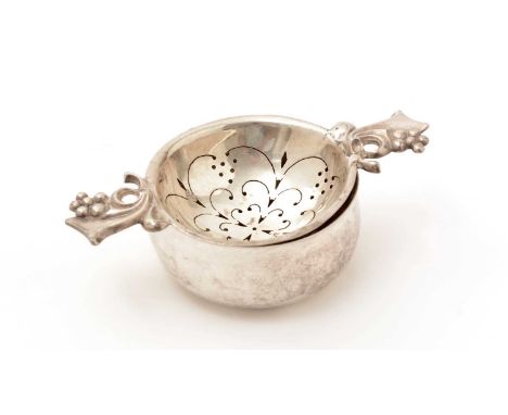 A George VI silver tea-strainer and drip bowl, with two fruiting scroll handles, by R. E. Stone, London, 1945/46, signed by S