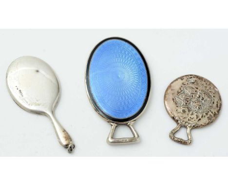 Three silver miniature or toy hand mirrors: a circular one with cherub masks by H. Matthews, Birmingham 1908; a plain oval ex