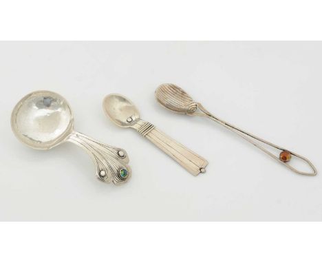 An arts and crafts silver caddy spoon with a shared and engraved stem, set with a cabochon enamelled boss flanked by two flat