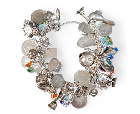 A silver charm bracelet with multiple charms, including carriage, Eiffel Tower, bird, European enamel shields, canoe, toby ju