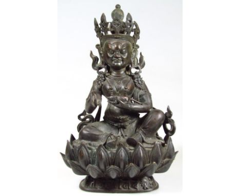 A Sino-Tibetan bronze figure of a deity, late 18thC/early 19thC, modelled seated on a lotus flower holding a mongoose, 29cm h