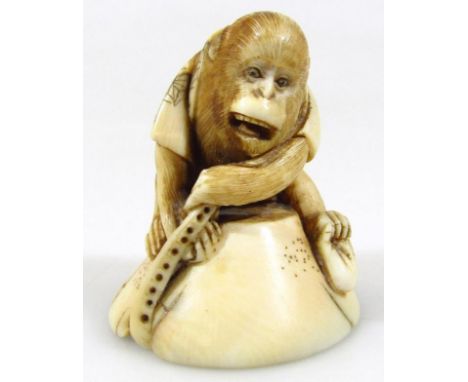 A late 19thC Japanese ivory netsuke, formed as a monkey, with carved octopus beneath, unsigned, 5cm high. 