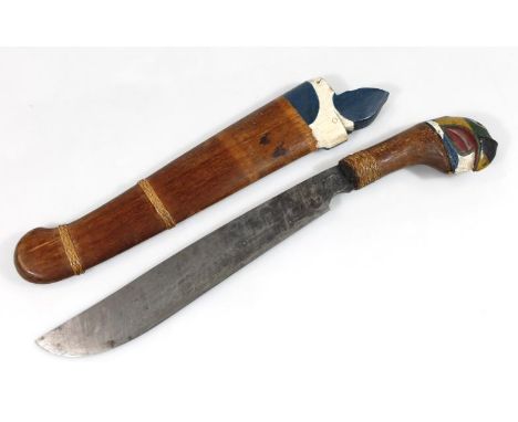 A hardwood cleaver knife, with part painted end, predominantly in yellow, green and blue with wooden scabbard and plain blade