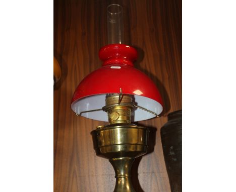 A BRASS PARAFFIN LAMP WITH RED GLASS SHADE