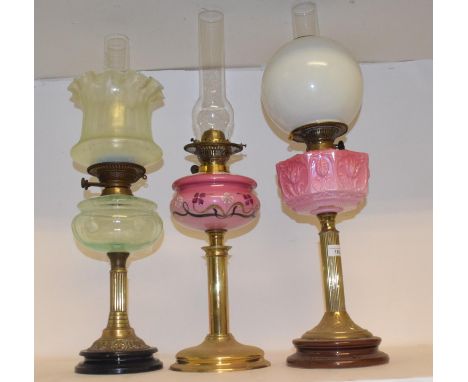 A late 19th/early 20th century brass and glass oil lamp, with pink glass well, and eight others (9)Green oil lamp, chips to s
